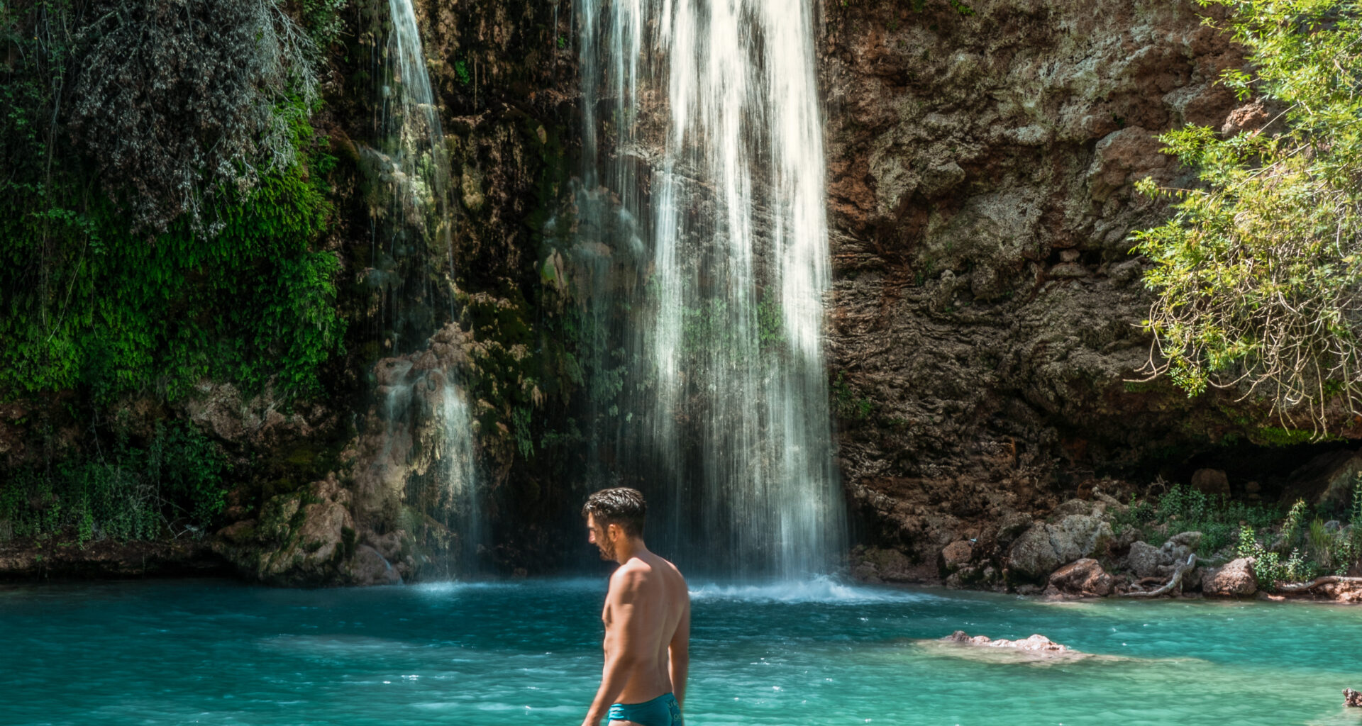 man swimming in waterfall