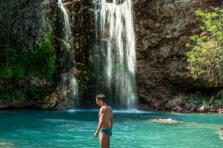 man swimming in waterfall